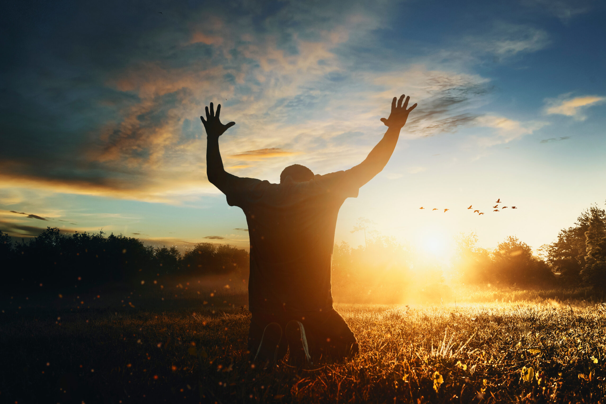 Grateful man man raising his hands in worship in the countryside.